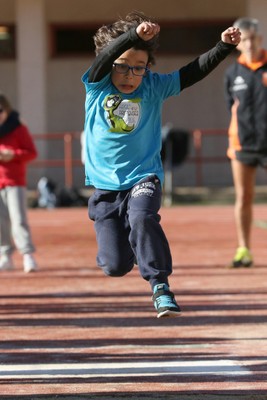 Un niño en pleno vuelo en un salto de longitud