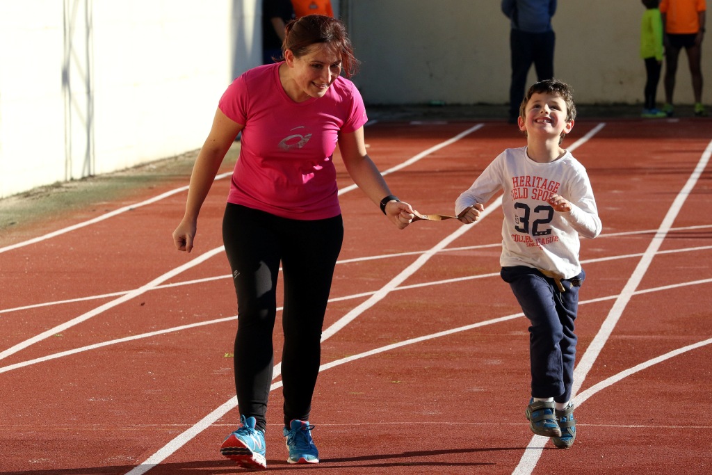 Una monitora ayuda a un niño ciego en un entrenamiento de carrera