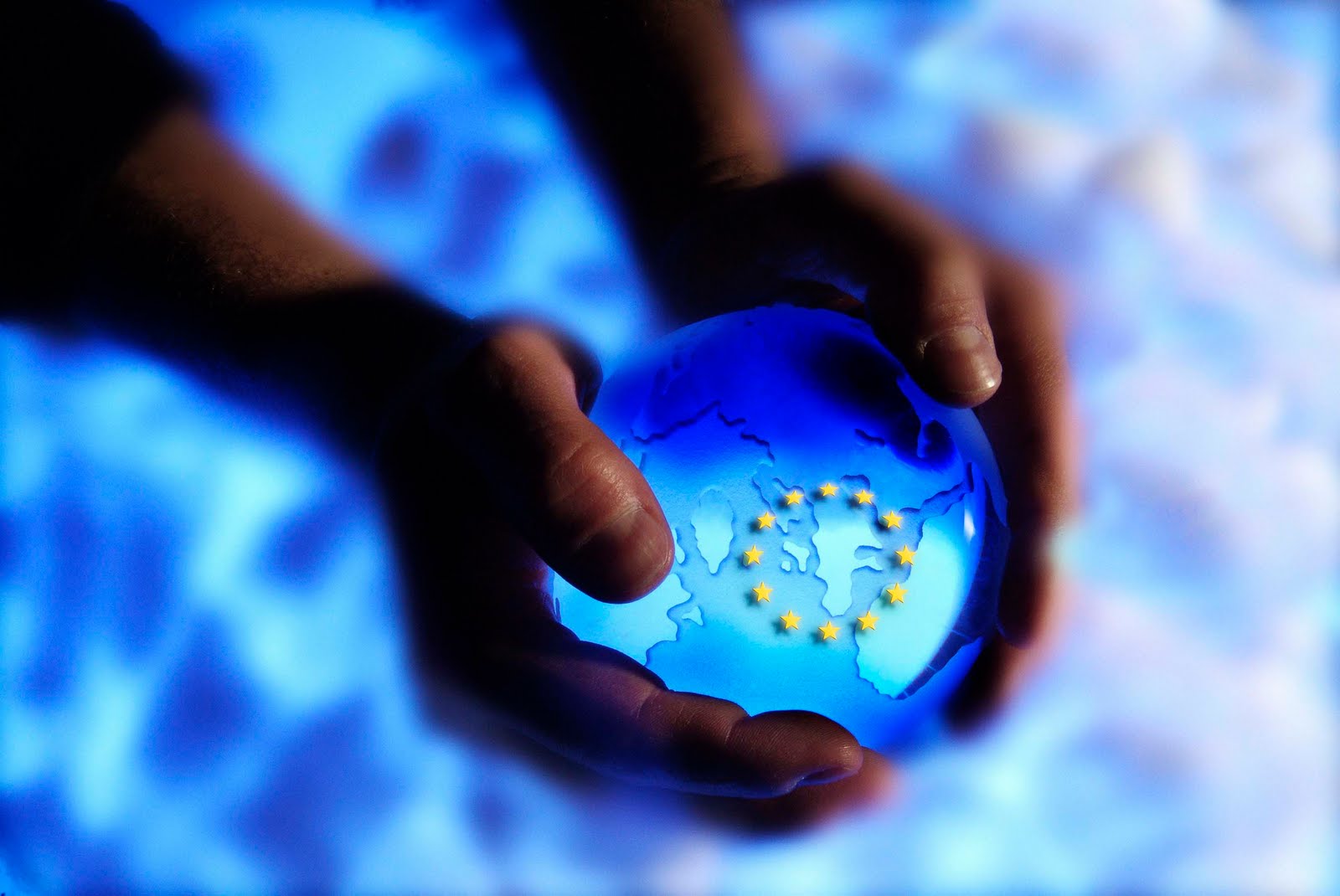 Unas manos sujetan la bola del mundo con las estrellas de la bandera europea 