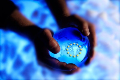 Unas manos sujetan la bola del mundo con las estrellas de la bandera europea 
