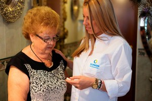 Una técnico de ILUNION enseña a una señora mayor el manejo del avisador para el servicio de teleasistencia