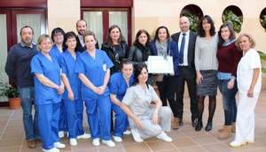 El personal del centro posa, a sus puertas, con el diploma acreditativo del reconocimiento