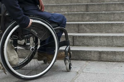 Persona en silla de ruedas ante una escalinata