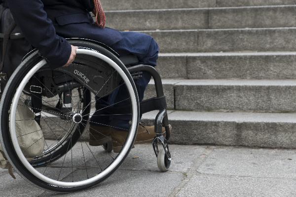 Persona en silla de ruedas ante una escalinata