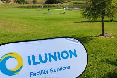 Una banderola de atención de ILUNION Facility Services en un campo de golf