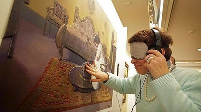 Una visitante de la exposición Mirar con Tacto explora con sus manos uno de los cuadros