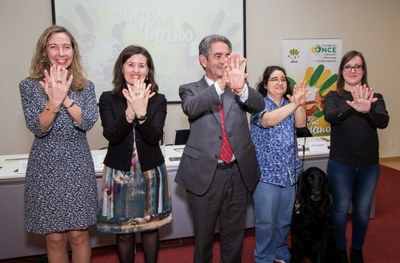 Revilla, en el centro de la imagen, junto a responsables de FOAPS, de la ONCE y Natalia Benito y su mediadora realizan el gesto "Coge mi mano" de la campaña