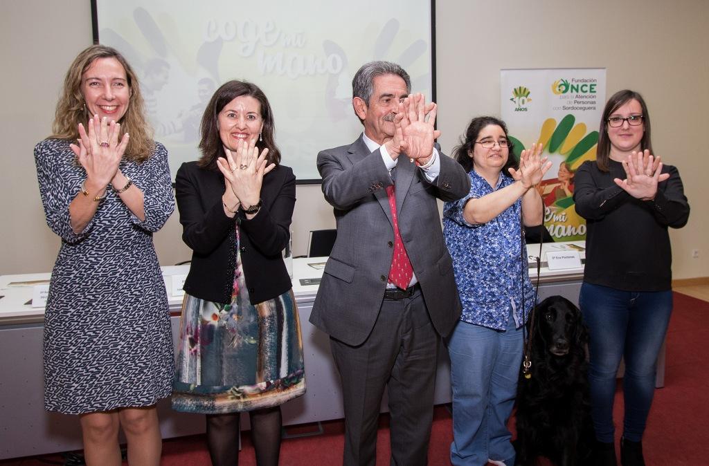 Revilla, en el centro de la imagen, junto a responsables de FOAPS, de la ONCE y Natalia Benito y su mediadora realizan el gesto "Coge mi mano" de la campaña
