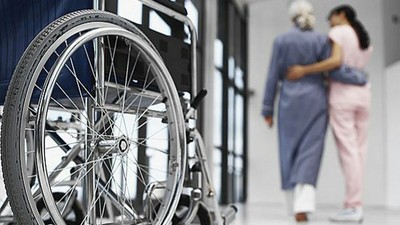 Primer plano de una silla de ruedas con dos personas al fondo de la imagen