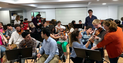 Alumnos de la ONCE sentados junto a los músicos de la orquesta de la UAX