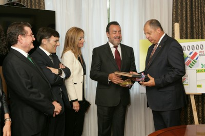 Miguel Carballeda recibe un libro de manos de  Solís Rivera sobre Costa Rica