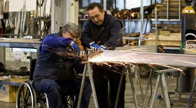 Dos trabajadores, uno de ellos con discapacidad (en silla de ruedas), durante una tarea en una empresa metalúrgica
