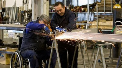 Dos trabajadores, uno de ellos con discapacidad (en silla de ruedas), durante una tarea en una empresa metalúrgica