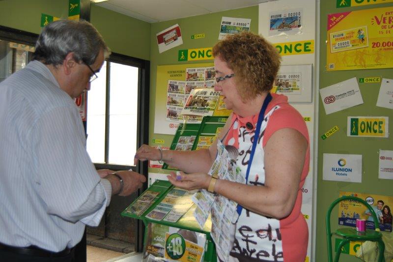 Rosa García vende a un cliente zaragozano uno de nuestros productos de juego, ante el puesto montado en el Mercado Central 