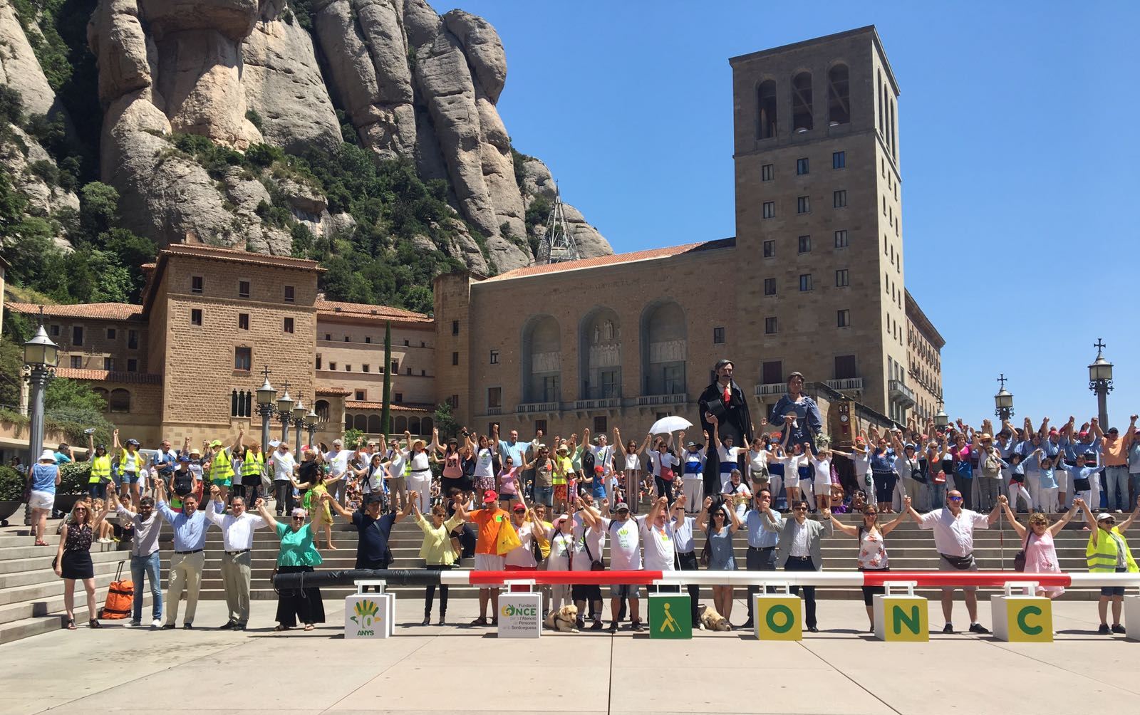 Afiliados y trabajadores catalanes posan en Montserrat ante un gran bastón rojo-blanco, símbolo de las personas sordociegas