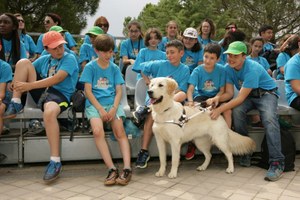 Un grupo de escolares acude, acompañados por un perro guía, a la exhibición de su movilidad que se montó en la Escuela