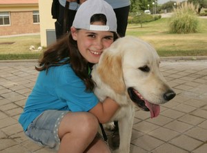 Una pequeña participante en el acto abraza a uno de los perros guía de la Escuela