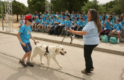 Uno de los alumnos, provisto de un antifaz, se deja conducir por un perro guía, acompañado por una instructora del centro