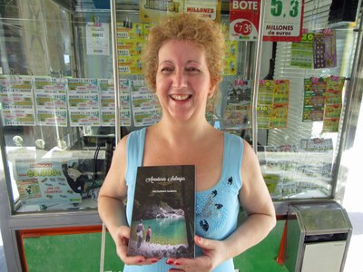Ana Cachinero muestra su libro delante del quiosco donde ejerce la venta de los productos de juego de la ONCE