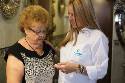 Una técnico de ILUNION Sociosanitario enseña a una señora mayor la utilización del dispositivo de teleasistencia