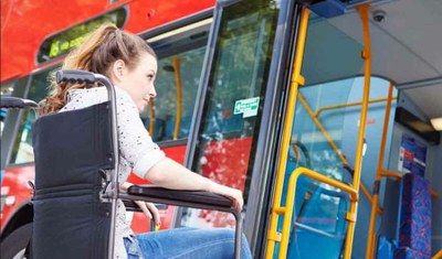 Primer plano de una chica en silla de ruedas frente a un autobús