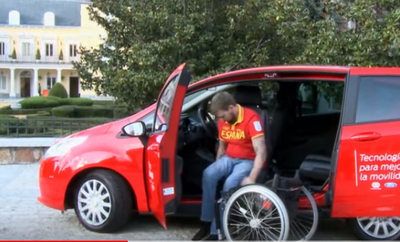 Una persona con discapacidad intenta incorporarse desde su silla de ruedas hasta el asiento del conductor