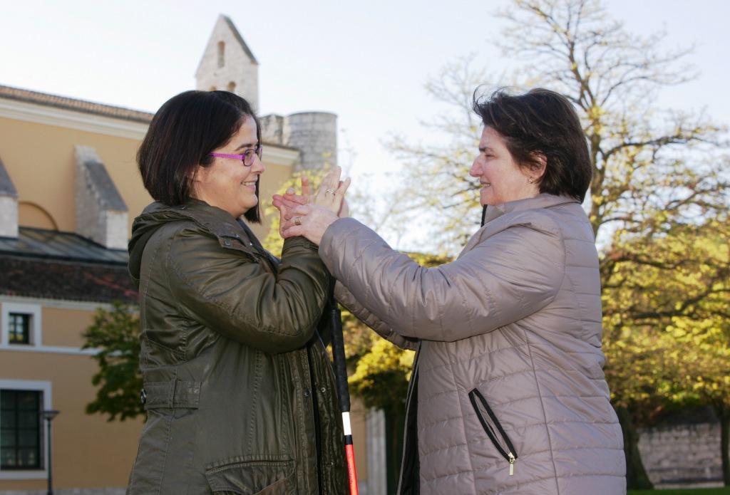 La sordociega Josefina Lavirgen (derecha) conversa, a través de sus manos, con su mediadora Tamara Busto