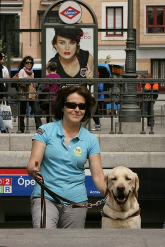 Adiestradora de la Escuela de Perros Guía de la FOPG saliendo con su perro por una de las bocas de metro en pleno centro de Madrid