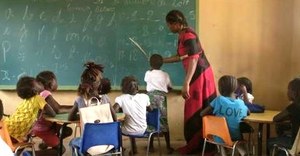 La profesora explica una lección con apoyo de le pizarra del aula