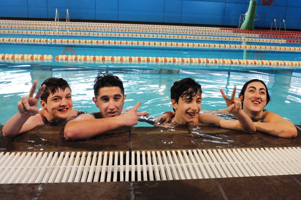 Un grupo de jóvenes afiliados se divierte en la piscina en una sesión de cursillo de Natación