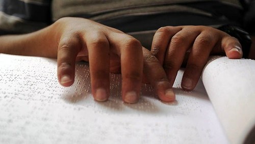 Las manos de un niño leen un texto braille