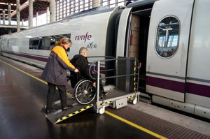 Un hombre en silla de ruedas sube en España a un tren AVE, con ayuda de una auxiliar y una rampa de acceso