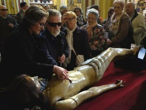 Personas ciegas observan con el tacto la talla de un Cristo