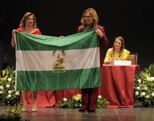 Carmen Aguilera (a la izquierda), en el momento de recoger la bandera andaluza que simboliza el galardón