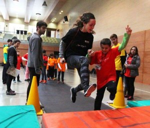 Un niño afiliado practica, junto a su monitora, el salto de longitud