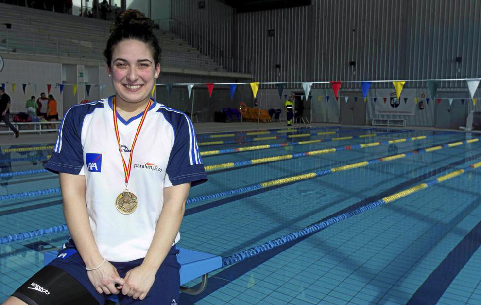 Ariadna, sonriente, al borde de la piscina, con una de sus medallas colgada al cuello