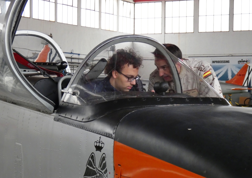Uno de los escolares es instruido por un militar sentado a los mandos de uno de los aviones de la escuadrilla