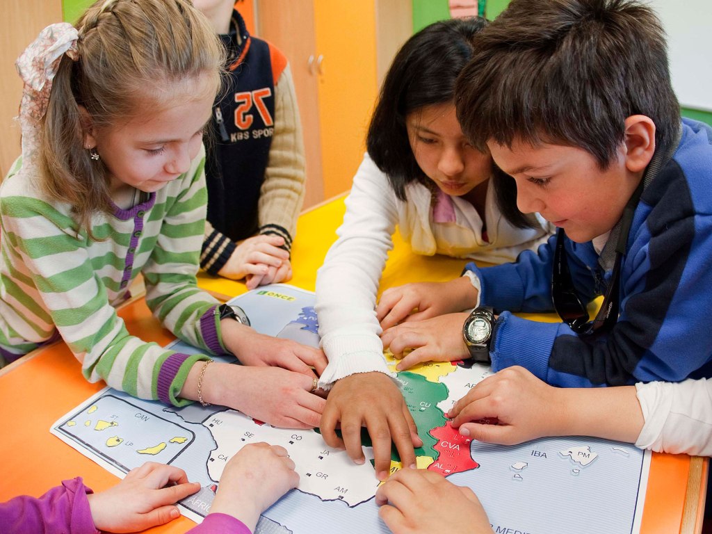Niños con y sin discapacidad visual trabajan en el aula con un mapa de España en relieve