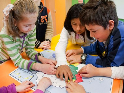 Niños con y sin discapacidad visual trabajan en el aula con un mapa de España en relieve