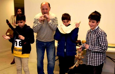 Felipe, el instructor, ensaya con tres niños afiliados los sonidos obtenidos con instrumentos primitivos