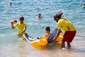 Dos voluntarios ayudan a entrar en el mar a una persona con movilidad reducida gracias a una 'silla anfibia' de baño