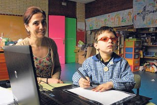 Un niño con discapacidad visual, junto a su profesora, en el aula