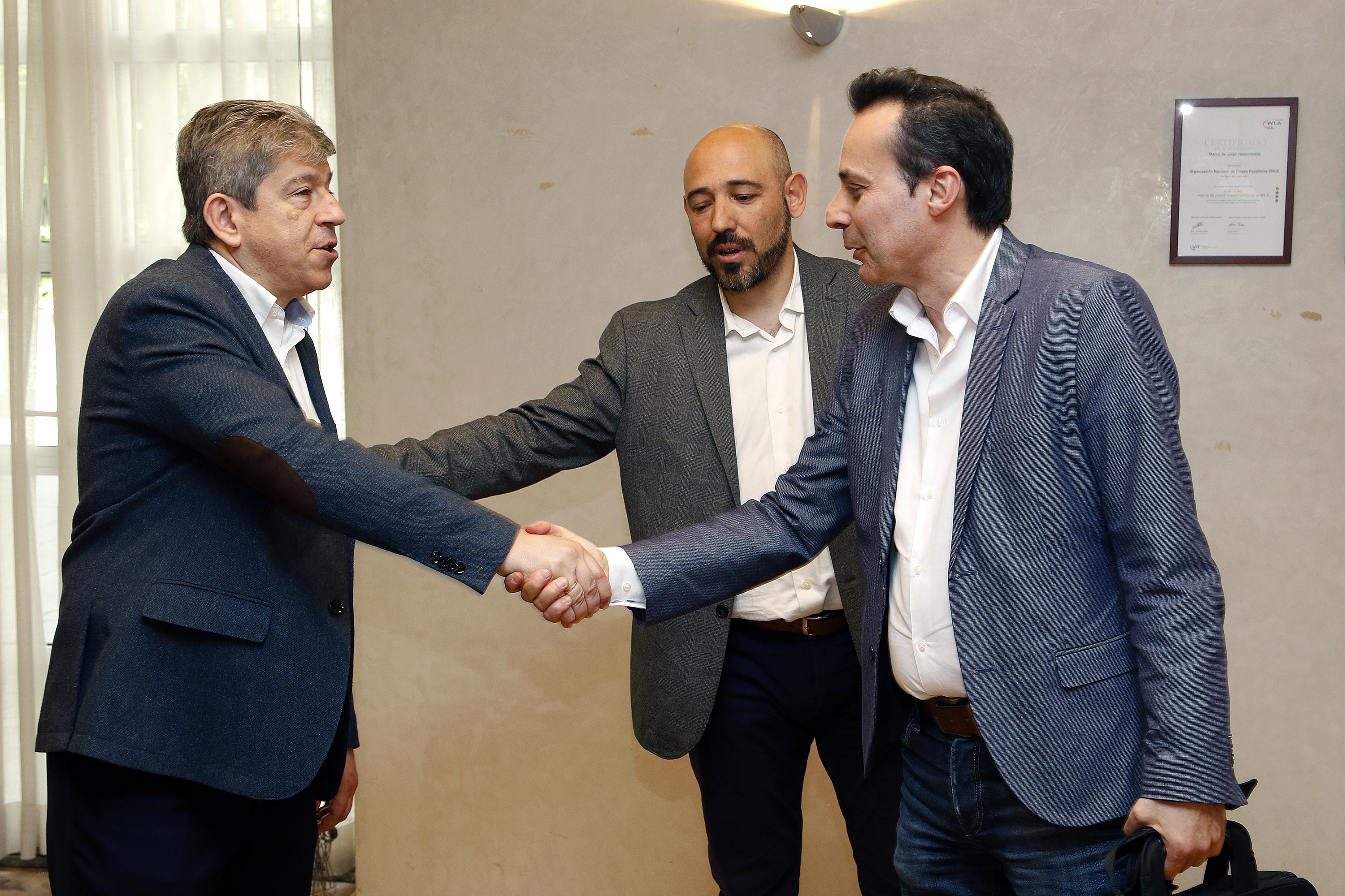 El escritor y periodista Carlos Fidalgo, jurado de Prensa impresa y digital, saluda al director de Comunicación de la ONCE, Antonio Mayor, en presencia de su jefe de Prensa, Chema Prieto