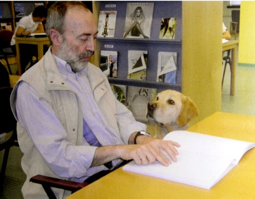 Luis Clemente leyendo en braille ante la atenta mirada de su primer perro guía