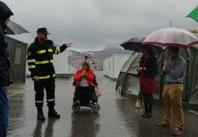 Un agente de la UME da instrucciones, bajo la lluvia, a un grupo de personas con discapacidad en materia de evacuación