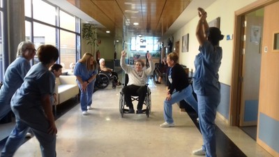 Un grupo de trabajadores calienta muscularmente con una paciente en silla de ruedas, durante una sesión de ejercicios en un centro atendido por ILUNION Sociosanitario
