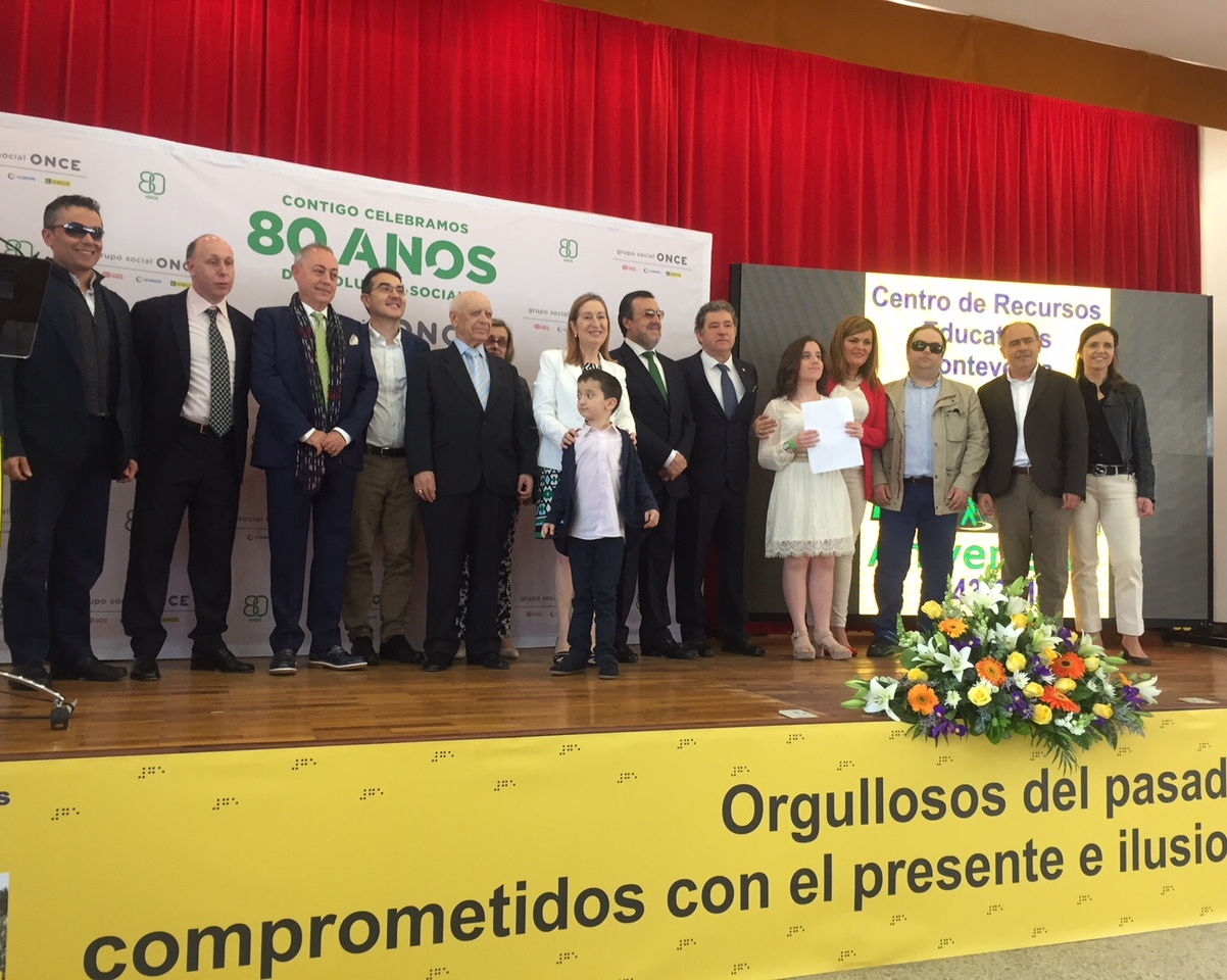Foto de familia, sobre el escenario, de autoridades y participantes en el acto institucional de la jornada festiva 