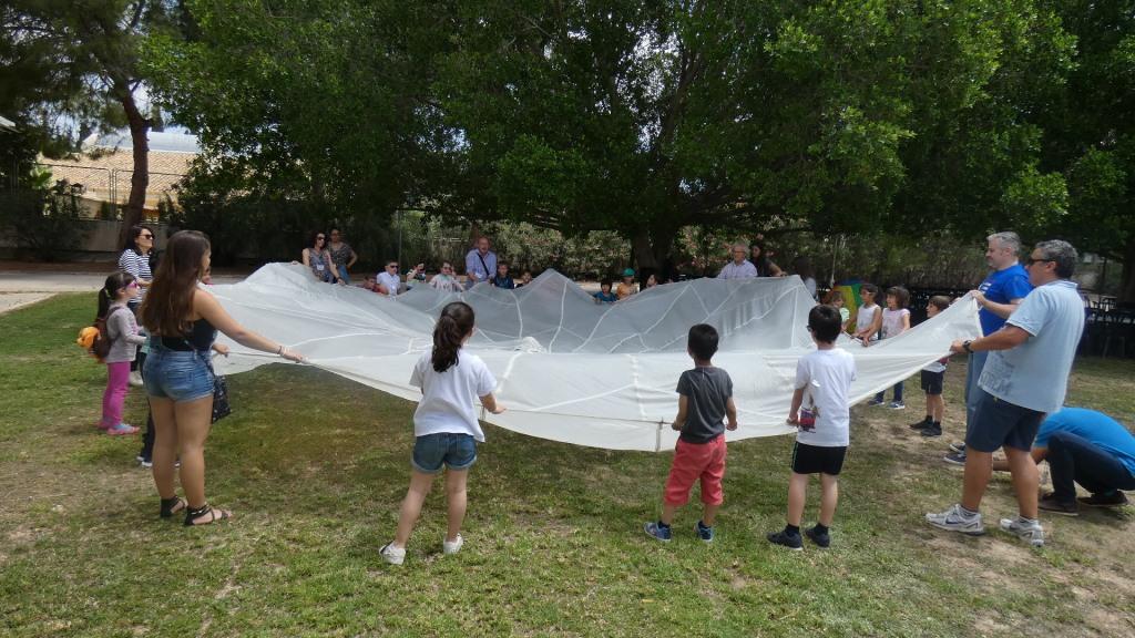 Niños y monitores despliegan en el jardín un gran retal de tela 