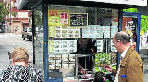 Varias personas, ante un quiosco de productos de juego de la ONCE