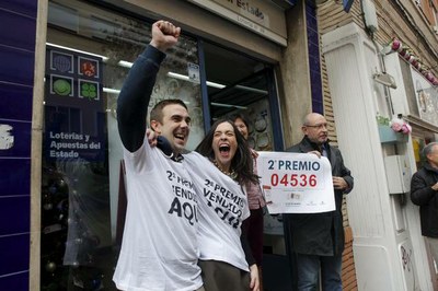 Varias personas celebran, a la puerta de una Administración de loterías del Estado, un premio de su sorteo de Navidad